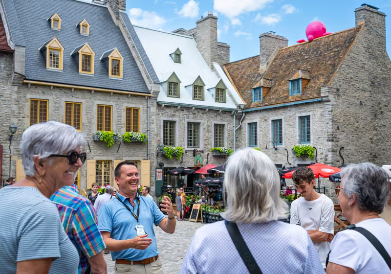 A guide laughing with visitors on Place Royale.